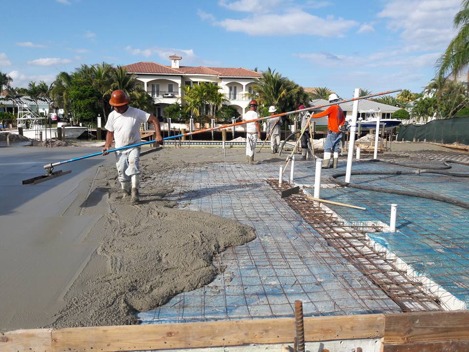 A group of men working on concrete in the process of pouring.